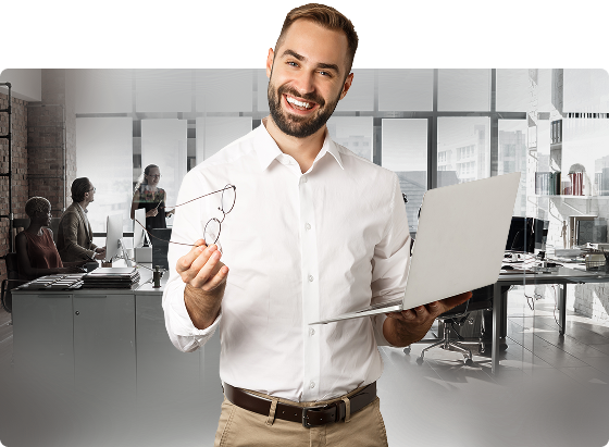 Man standing with a laptop, reviewing documents or an application.